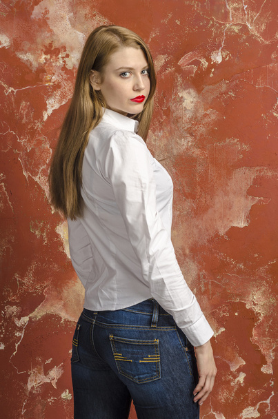 Young beautiful long-haired brown-haired woman in unbuttoned white shirt and jeans - Fotó, kép