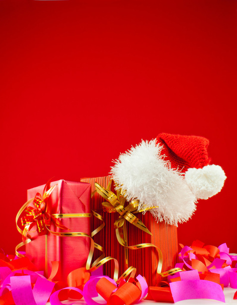 Prezenty z kapelusz Świętego Mikołaja na czerwonym tle - Zdjęcie, obraz