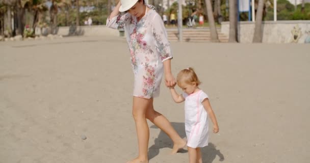 Мать со своей дочерью, гуляющей по пляжу
 - Кадры, видео
