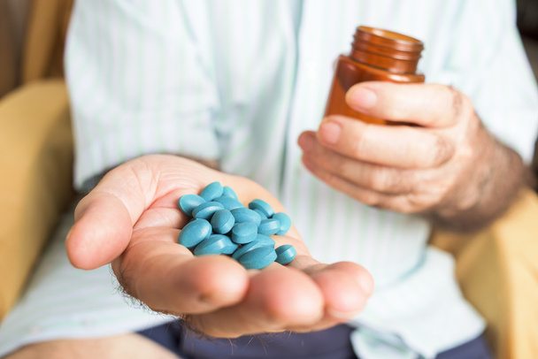 γέρος με ένα σωρό μπλε χάπια στο χέρι του - Φωτογραφία, εικόνα