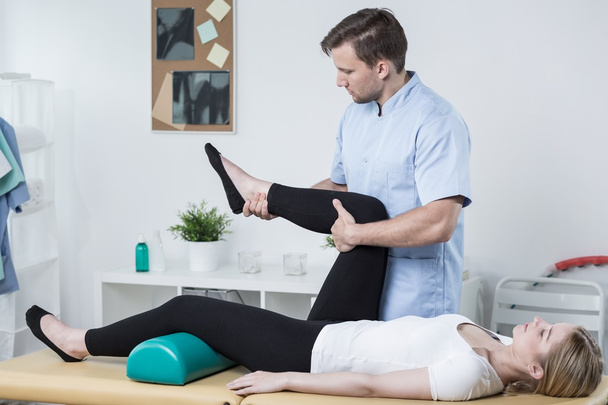 Male physiotherapist exercising with patient - Foto, afbeelding