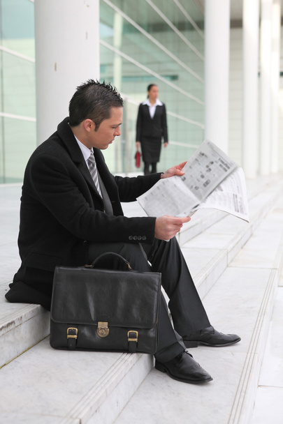 Businessman reading a newspaper outside an office building - Foto, afbeelding