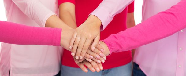 close up of women in pink shirts with hands on top - Foto, imagen