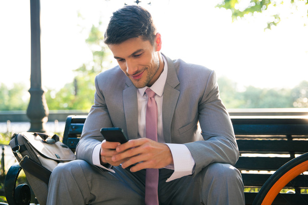 Happy businessman using smartphone outdoors - Foto, Bild