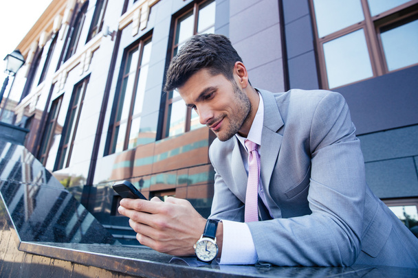 Businessman using smartphone outdoors - Zdjęcie, obraz