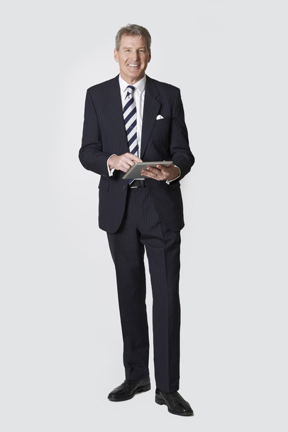 Studio Portrait Of Mature Businessman Holding Digital Tablet - Фото, изображение