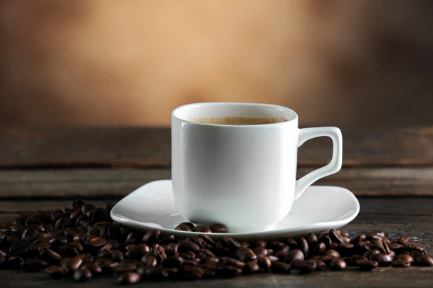 Cup of coffee and beans on blurred background - Foto, imagen