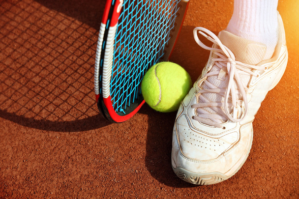 Las piernas del hombre cerca de la raqueta de tenis y pelotas
 - Foto, imagen