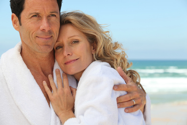 Couple embracing by the sea in toweling robes - Foto, imagen