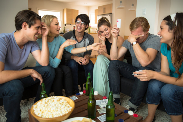Game night poker playing friends loser embarrassed and winner celebrates at party - Foto, Bild