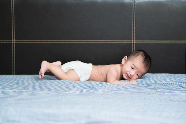 Cute Asian baby lying on a white pillow, on bed - Zdjęcie, obraz