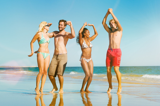 Vrienden springen op oceaan strand in vakantie - Foto, afbeelding
