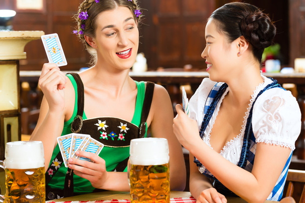 friends drinking beer in Bavarian pub playing cards - Photo, Image