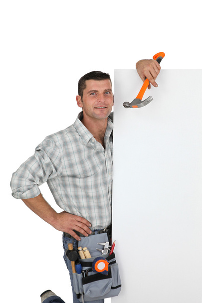 Handyman holding a hammer and a blank sign - 写真・画像