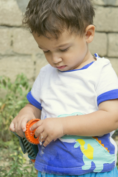 Хлопчик грає з садовим шлангом
 - Фото, зображення