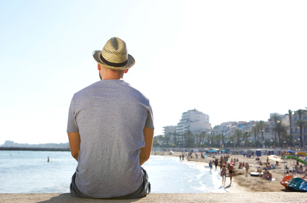 Retrato de detrás de un hombre sentado solo mirando la playa
  - Foto, Imagen