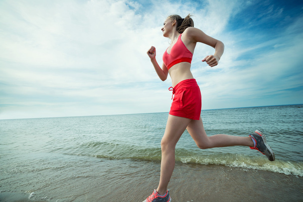 Fiatal hölgy futás a napsütéses nyári homokos strandon. Edzés. Jog - Fotó, kép