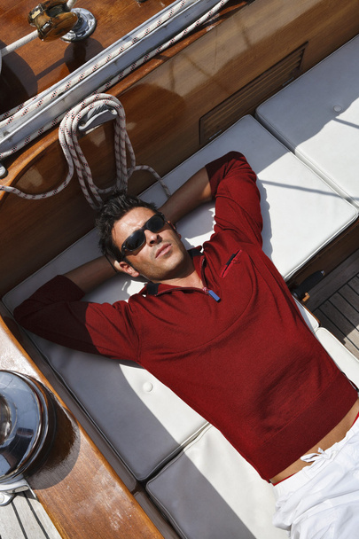 Italy, Tuscany, young sailor is resting on a wooden sailing boat - Valokuva, kuva