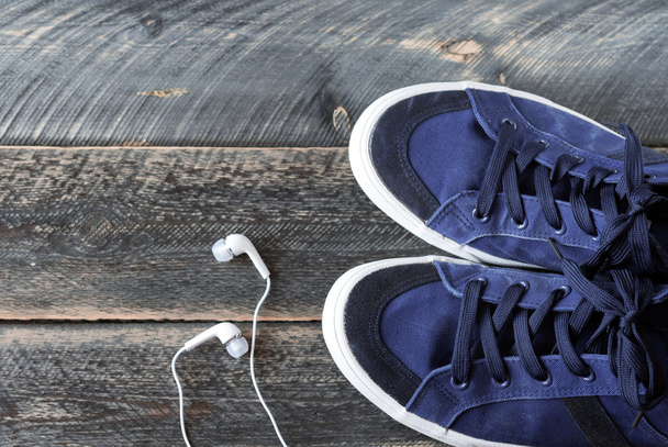 Sneakers and earphones on old wooden background - Photo, Image