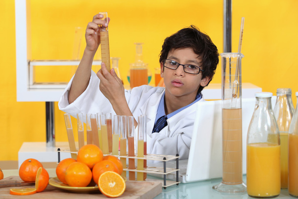 Little boy conducting experiment on orange juice - Fotó, kép
