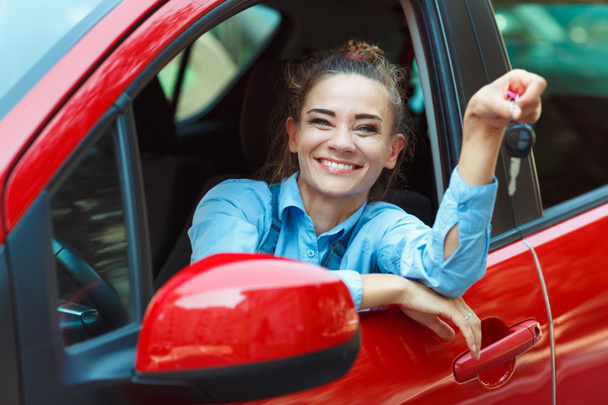 Jeune femme joyeuse assise dans une voiture avec des clés à la main
 - Photo, image