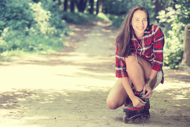 Girl going rollerblading sitting putting on in line skates outdoors - Foto, immagini