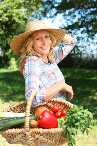 Pretty woman with a straw hat and basket of vegetables. - Zdjęcie, obraz