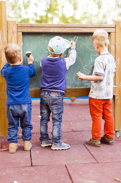 Three boys drawing on a blackboard - Zdjęcie, obraz