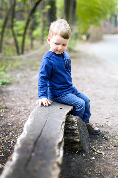 Boy sitting on a wooden bench - Fotó, kép