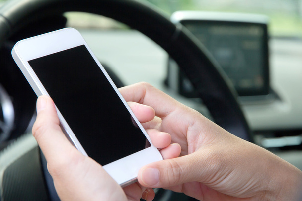 Молодая женщина держит мобильное устройство в машине
 - Фото, изображение