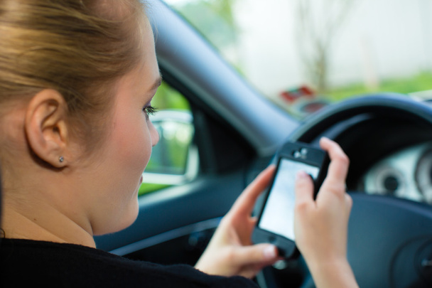 Молодая женщина в машине с мобильным телефоном
 - Фото, изображение