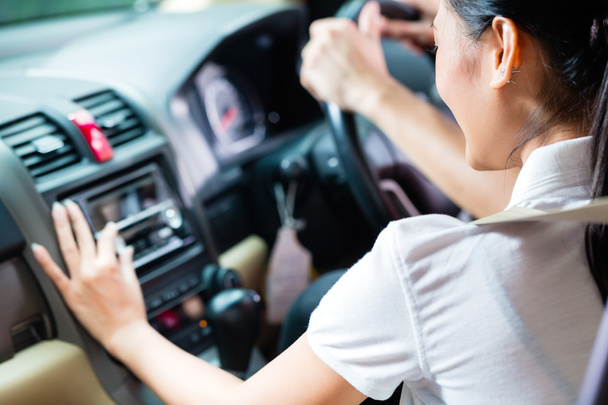 カップルの女性はラジオをオン新しい車を運転して - 写真・画像