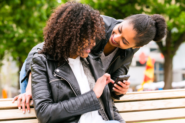 friends chatting with smartphone on park bench - Photo, image