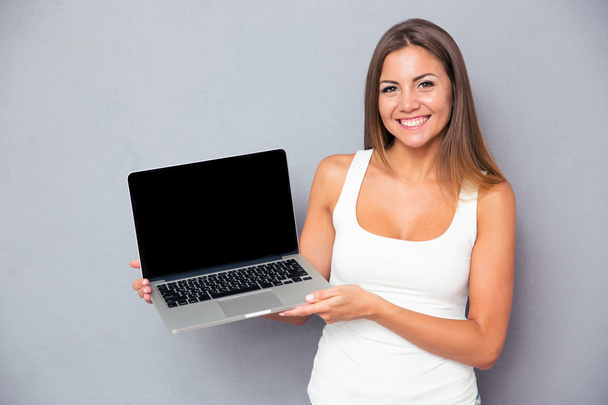 Happy girl showing blank laptop screen - 写真・画像