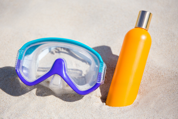 diving mask and suntan lotion bottle on sandy beach - Photo, Image