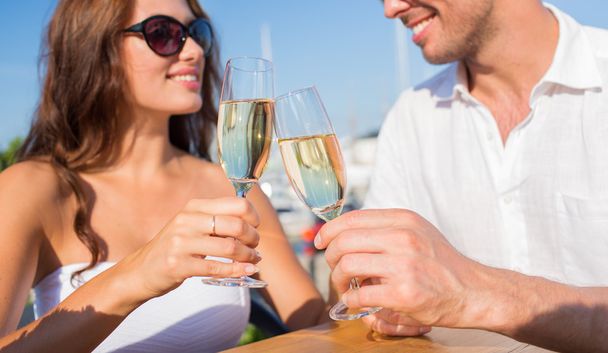 smiling couple clinking champagne glasses at cafe - Fotó, kép