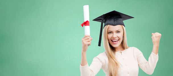 student in trencher cap with diploma over green - Foto, imagen