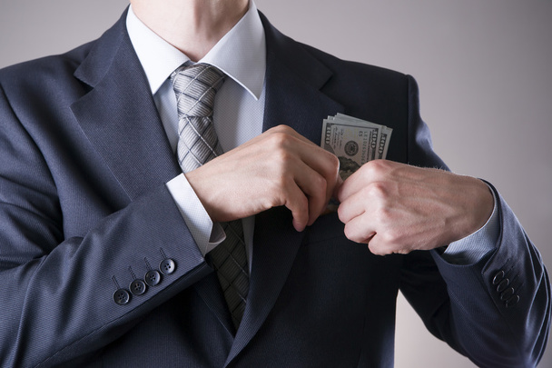 Businessman with money in studio on a gray background - Foto, Bild