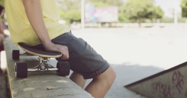 Man sitting on a skateboard balanced on a wall - Footage, Video