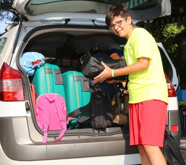 niño sonriente carga bolsas en el vagón de equipaje
 - Foto, imagen