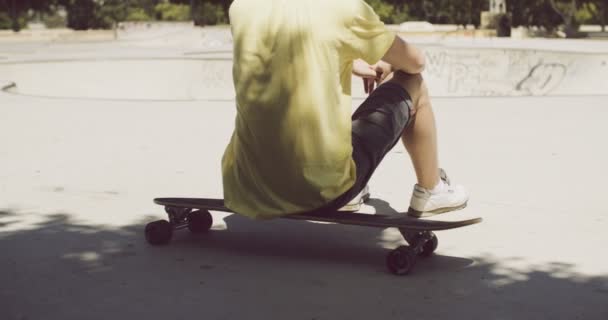 Homem sentado em seu longboard em um parque de skate
 - Filmagem, Vídeo