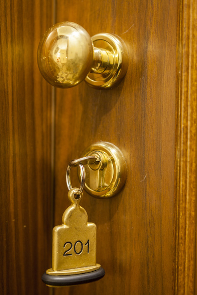 Δωμάτιο ξενοδοχείου κλειδί ξαπλωμένος στο κρεβάτι με μπρελόκ - Φωτογραφία, εικόνα