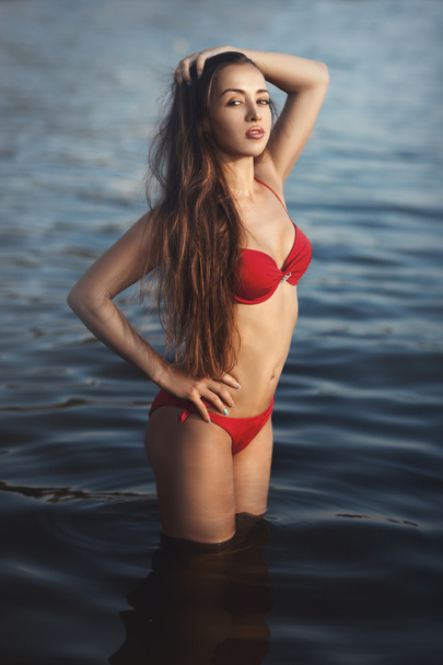 Girl in a red bathing suit standing water. - Photo, Image