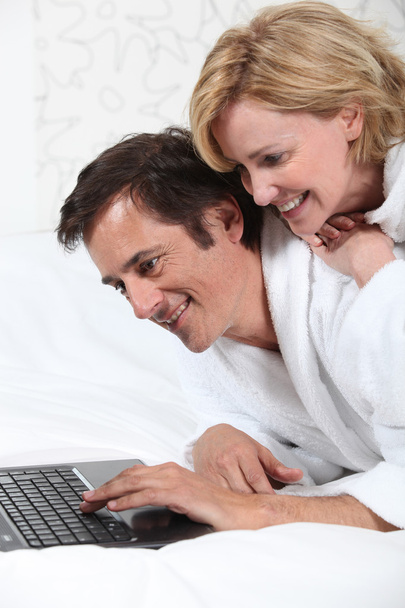 Couple on laptop in dressing gown. - Foto, Imagen