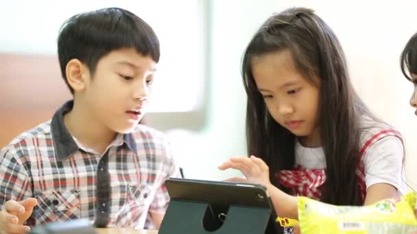 Küçük Asyalı çocuk grubu aperatif yeme ve bir bilgisayar tablet imizle birlikte oynuyor . - Video, Çekim