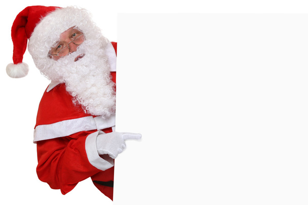 Santa Claus pointing on Christmas at empty banner with copyspace - Foto, Imagen