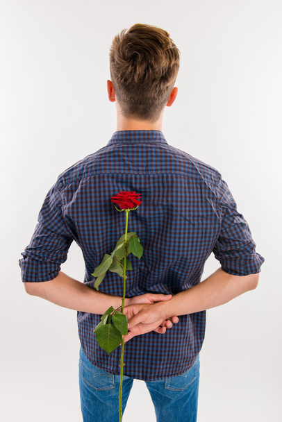 man hiding behind his back a red rose - Foto, Imagem