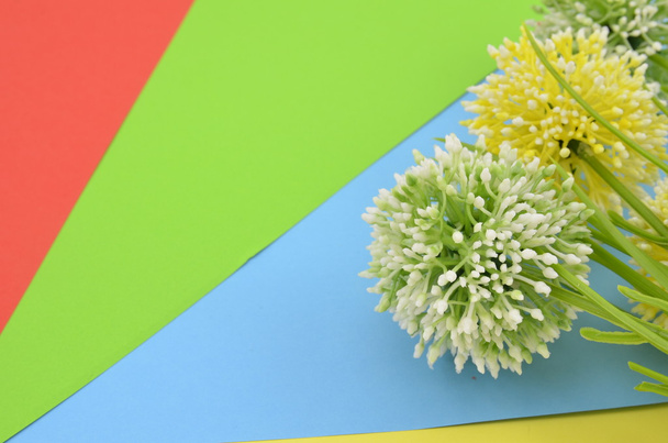 τέσσερις τεχνητό πράσινο και κίτρινο λουλούδι σε μπλε, πράσινο και κίτρινο φόντο - Φωτογραφία, εικόνα