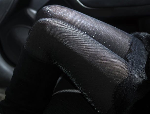 Slanke sexy benen in glanzende panty in auto - Foto, afbeelding