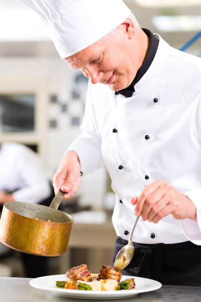 Chef in restaurant kitchen preparing food - Фото, изображение